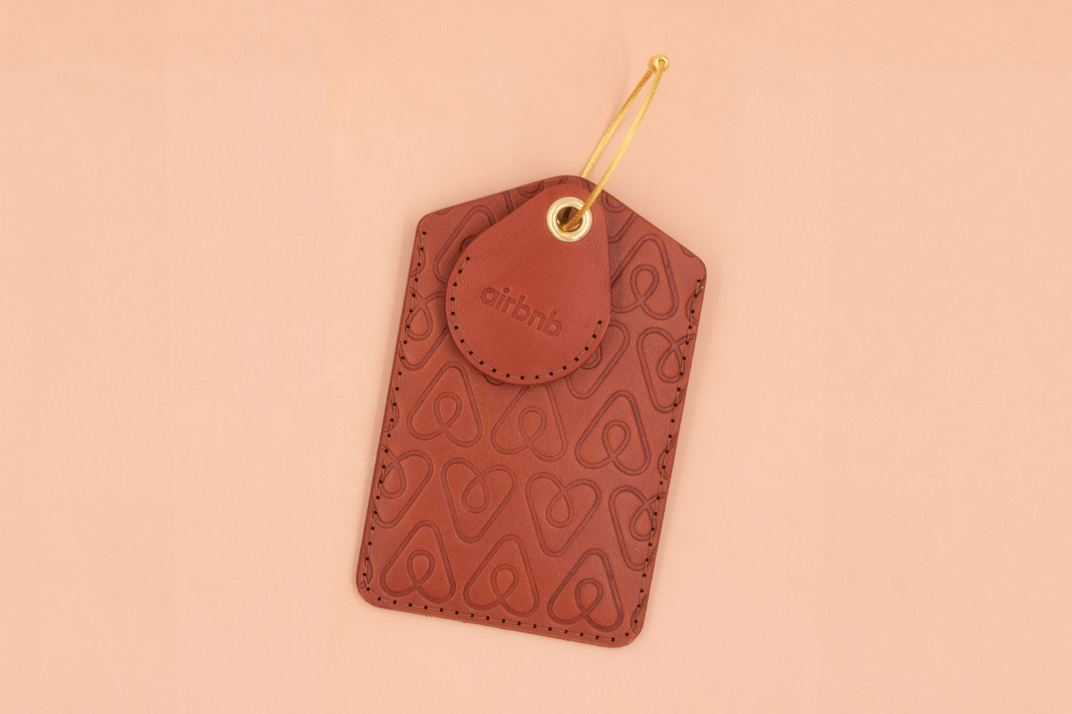 Brown leather Executive Luggage Tag and AirTag case with brass hardware and Airbnb logo.
