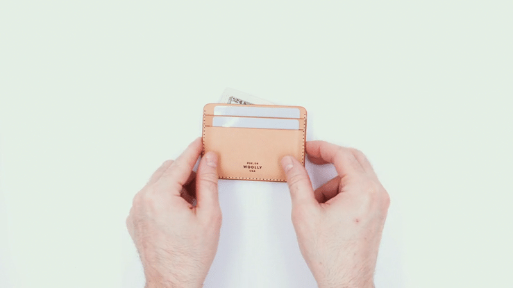 Video of two hands showing 360 degree view of natural leather Half wallet with blank cards and a $20 bill
