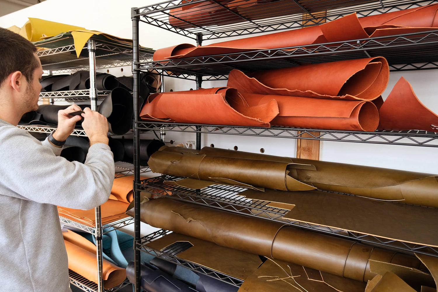 Cofounder Jake standing in front of shelves holding rolls of leather hides.