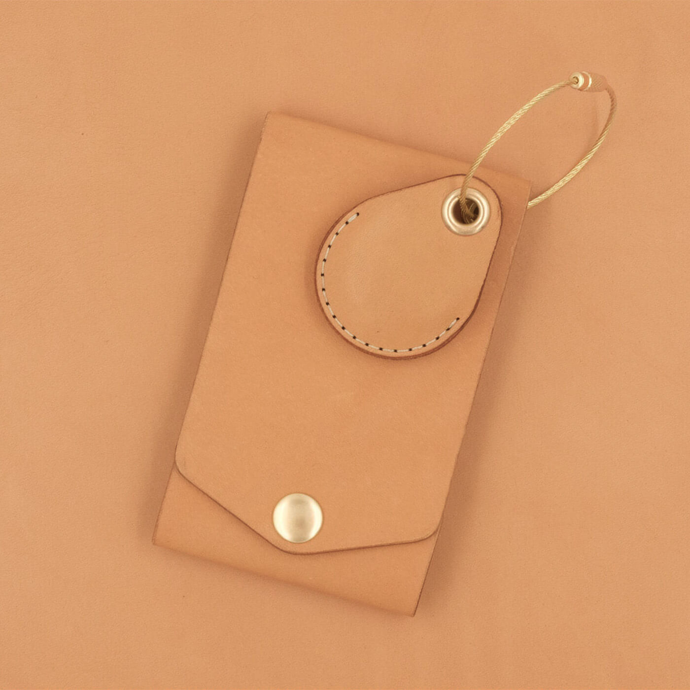 Tan leather luggage tag with fold closure, brass hardware, and tan leather AirTag case.