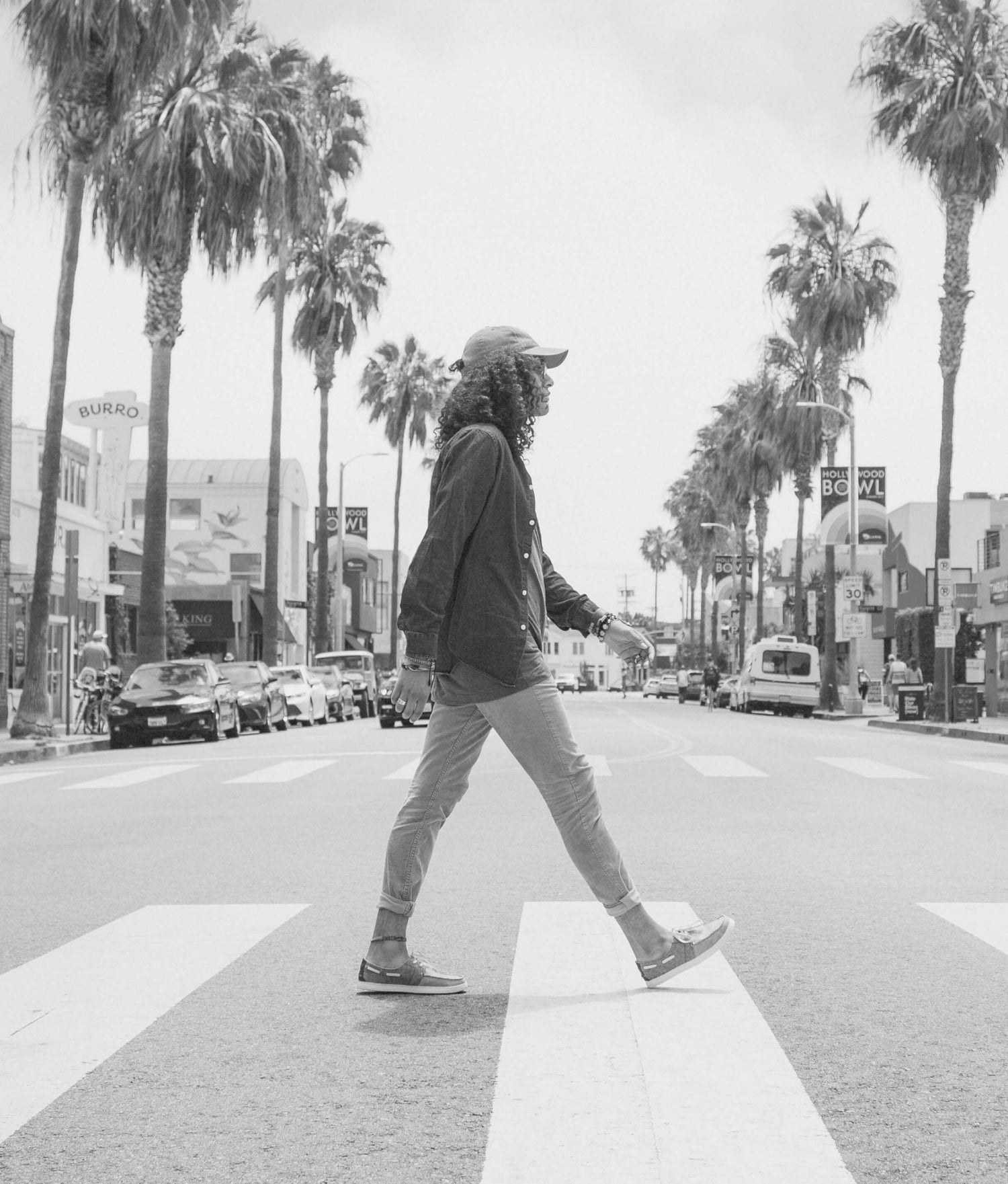 Black and white photo of person walking across a crosswalk.