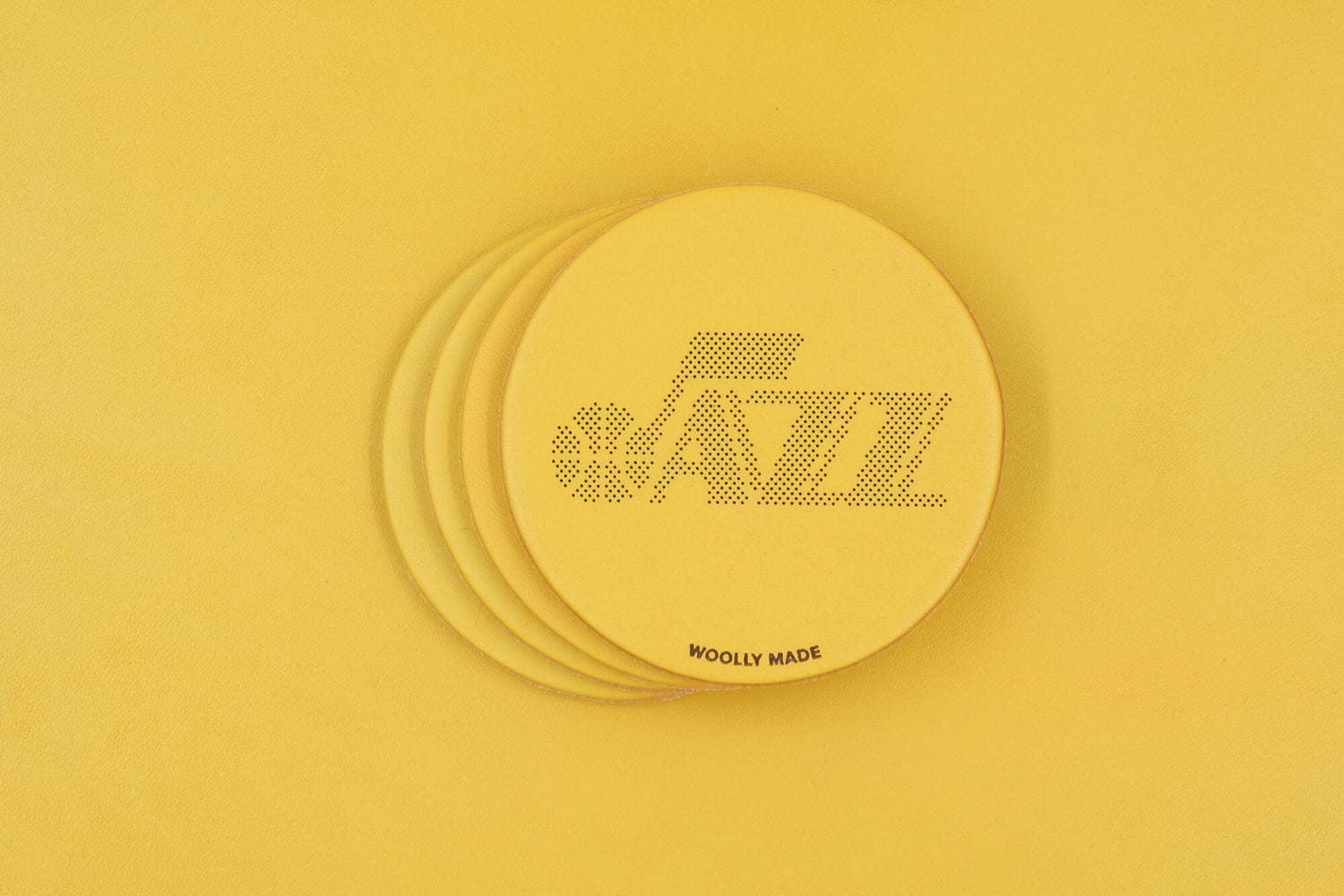 Stack of yellow leather round coasters with Utah Jazz and Woolly Made logos.