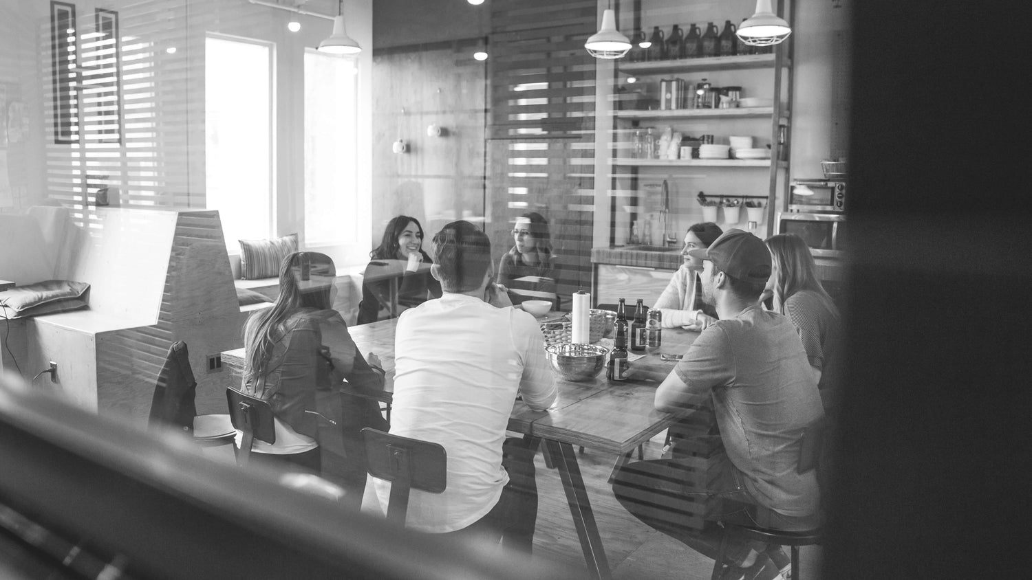 Black and white photo of people meeting around a table.
