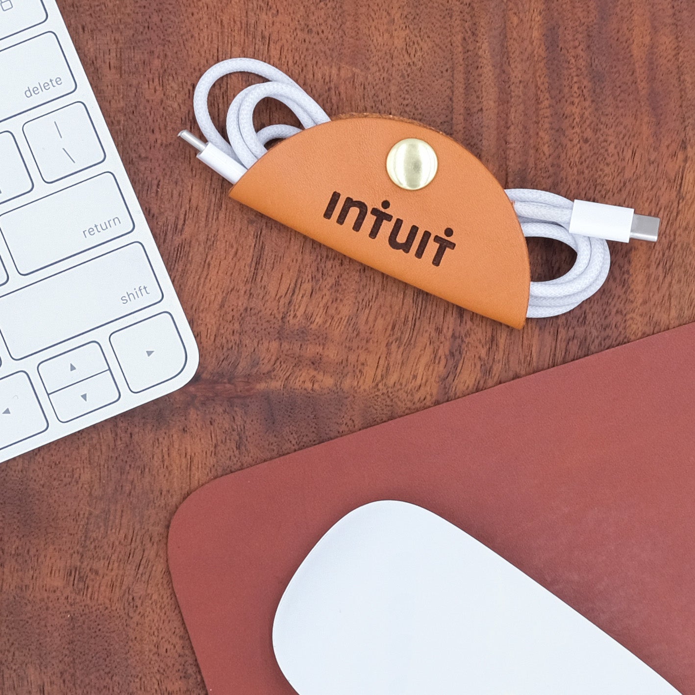 Branded Intuit laser-engraved cord wrap for promotional gifting displayed on a table.