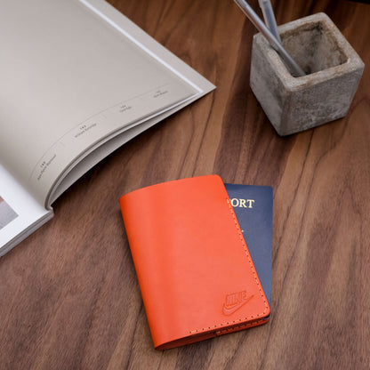 Woolly Made Passport Cover debossed for promotional gifting. On a dark wood table and a concrete pen holder.