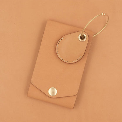 Tan leather luggage tag with fold closure, brass hardware, and tan leather AirTag case.