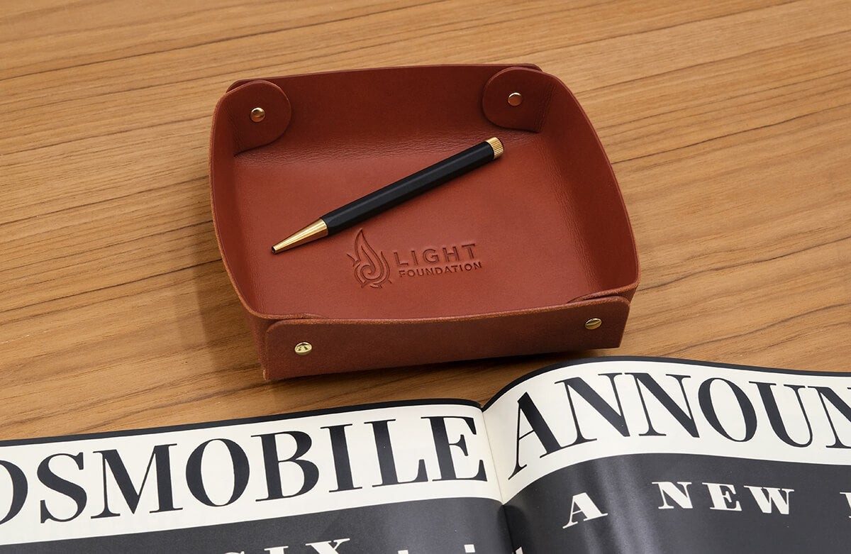 Valet Tray in brown leather with a debossed logo.