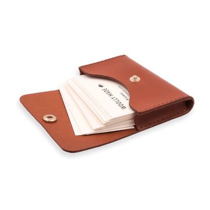 Brown leather with stitching, a fold, and brass snap closure showed open with business cards.