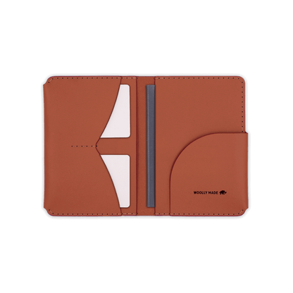 Brown leather passport wallet open view with Woolly Made logo, passport and white cards.