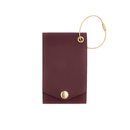 Burgundy leather luggage tag with fold closure and brass hardware.