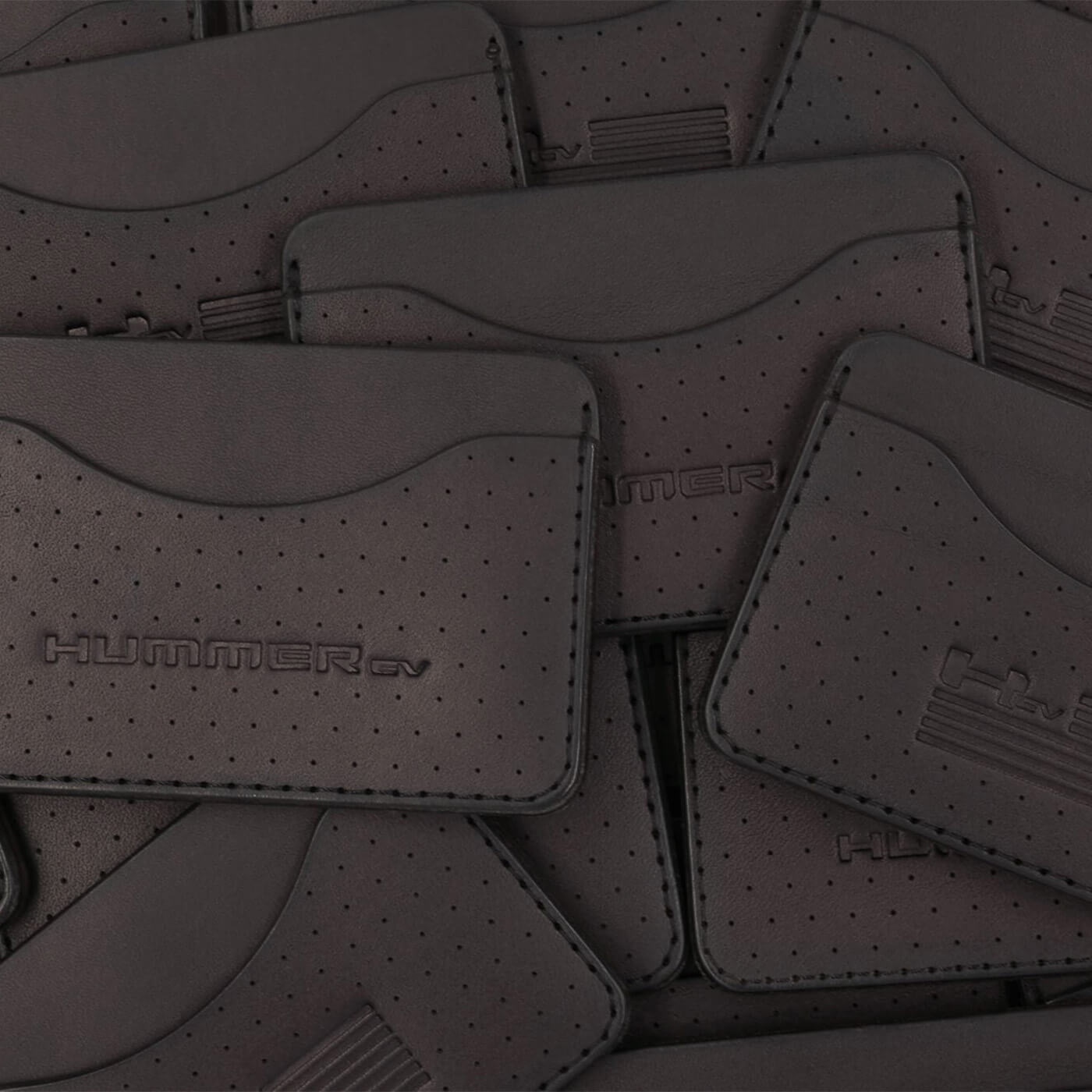 Pile of black leather Slim Wallets with decorative perforation and Hummer logos.