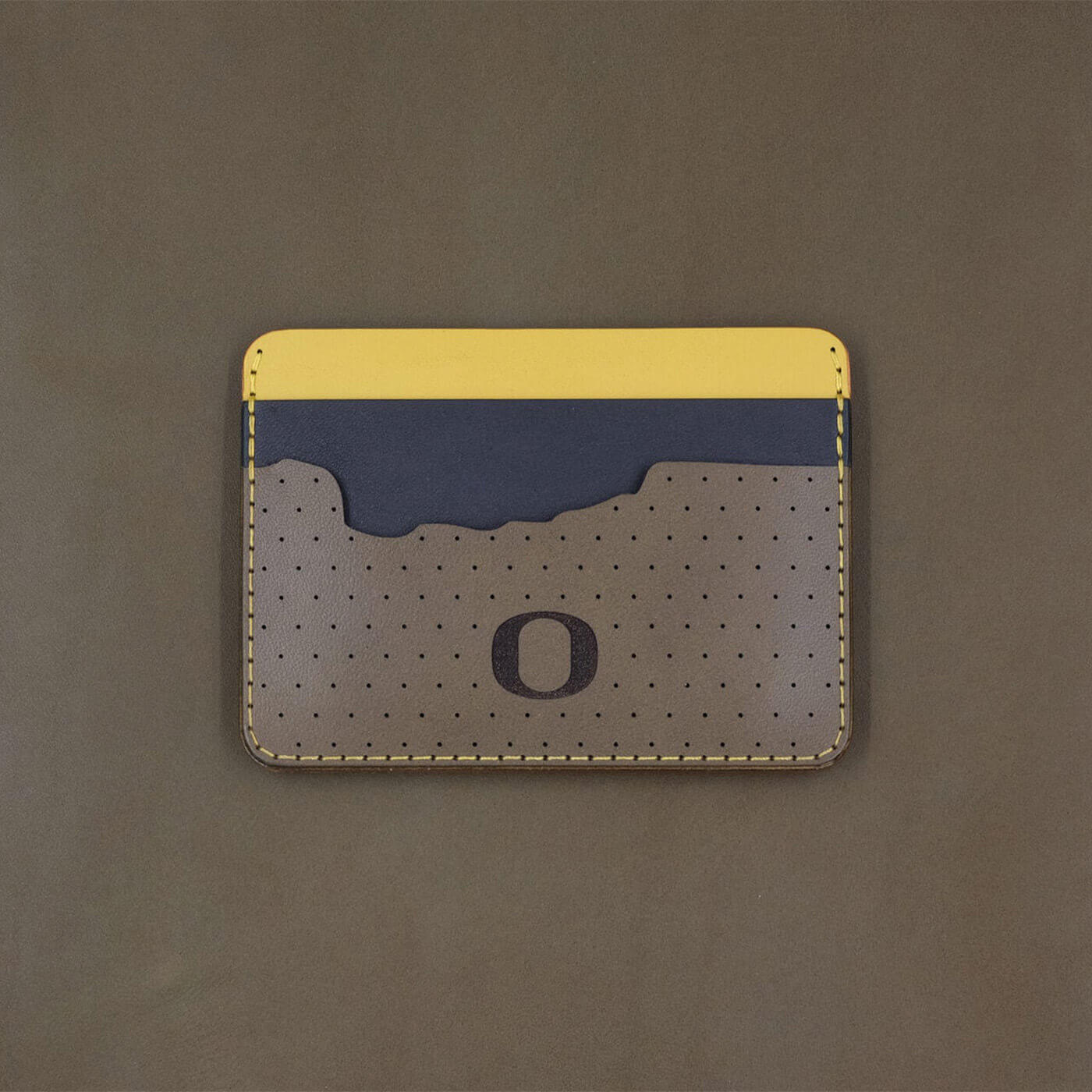 Olive, navy, and yellow leather half wallet with state of Oregon-shaped pocket with University of Oregon logo.