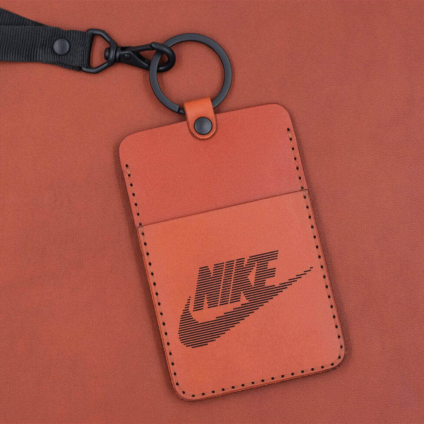 Brown leather ID Badge Holder with pocket, black hardware and lanyard, and Nike logo.