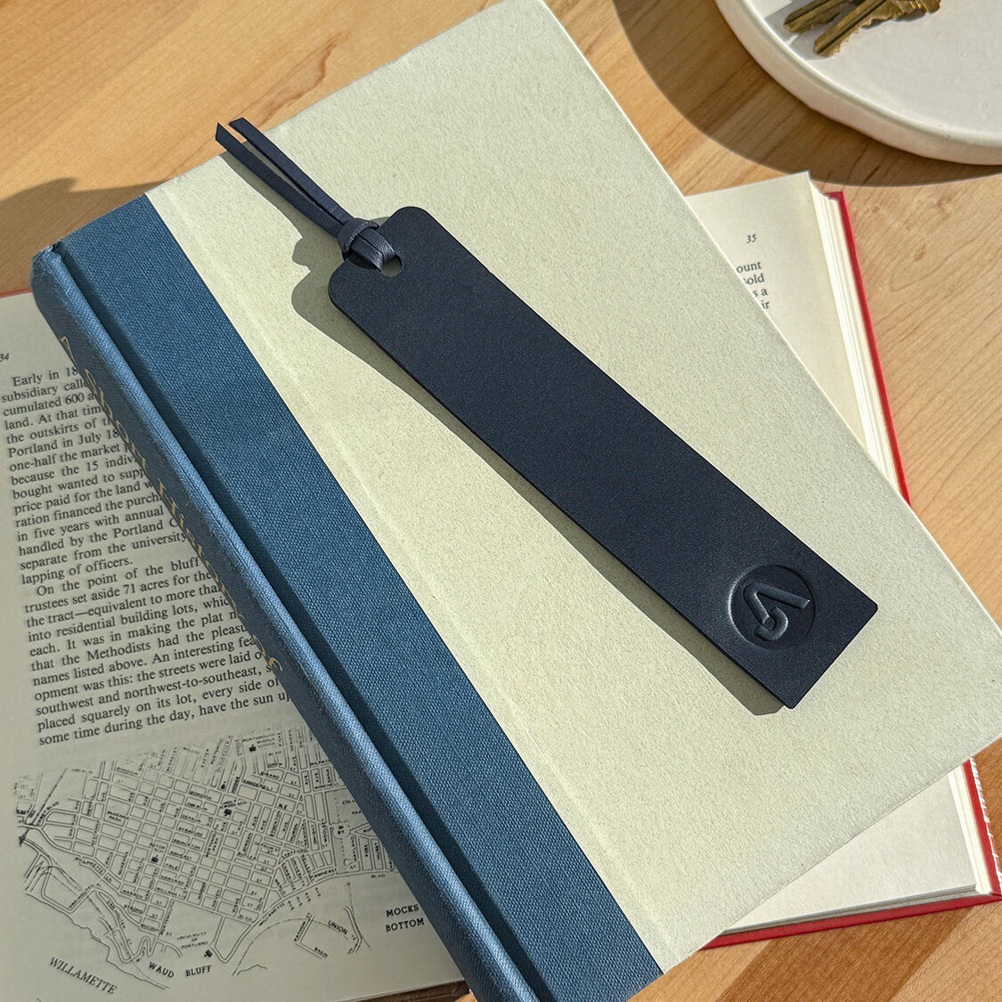 Navy leather tassel bookmark with debossed corporate logo, ideal for promotional gifting.