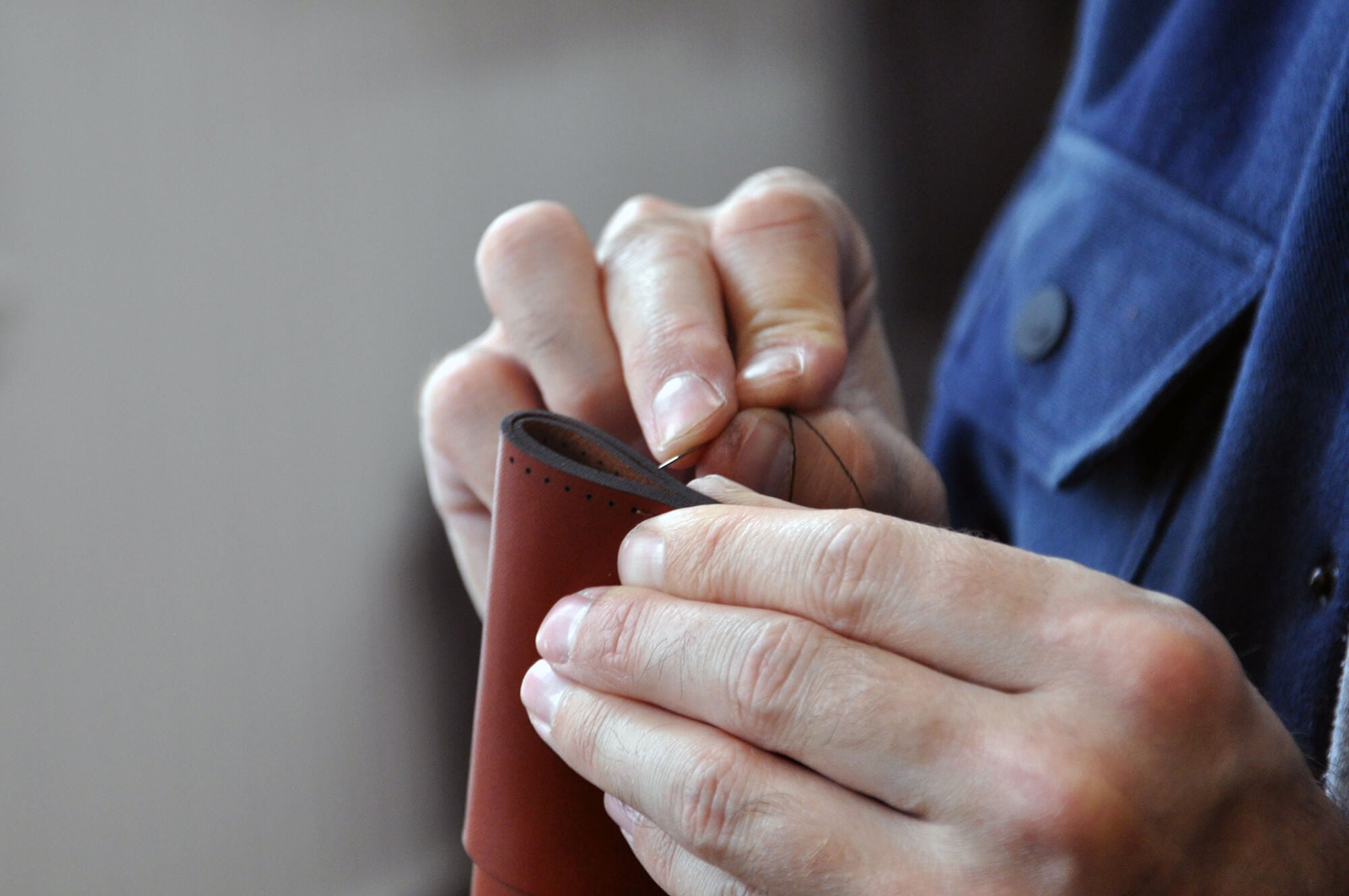 Hands stitching a Half Wallet.