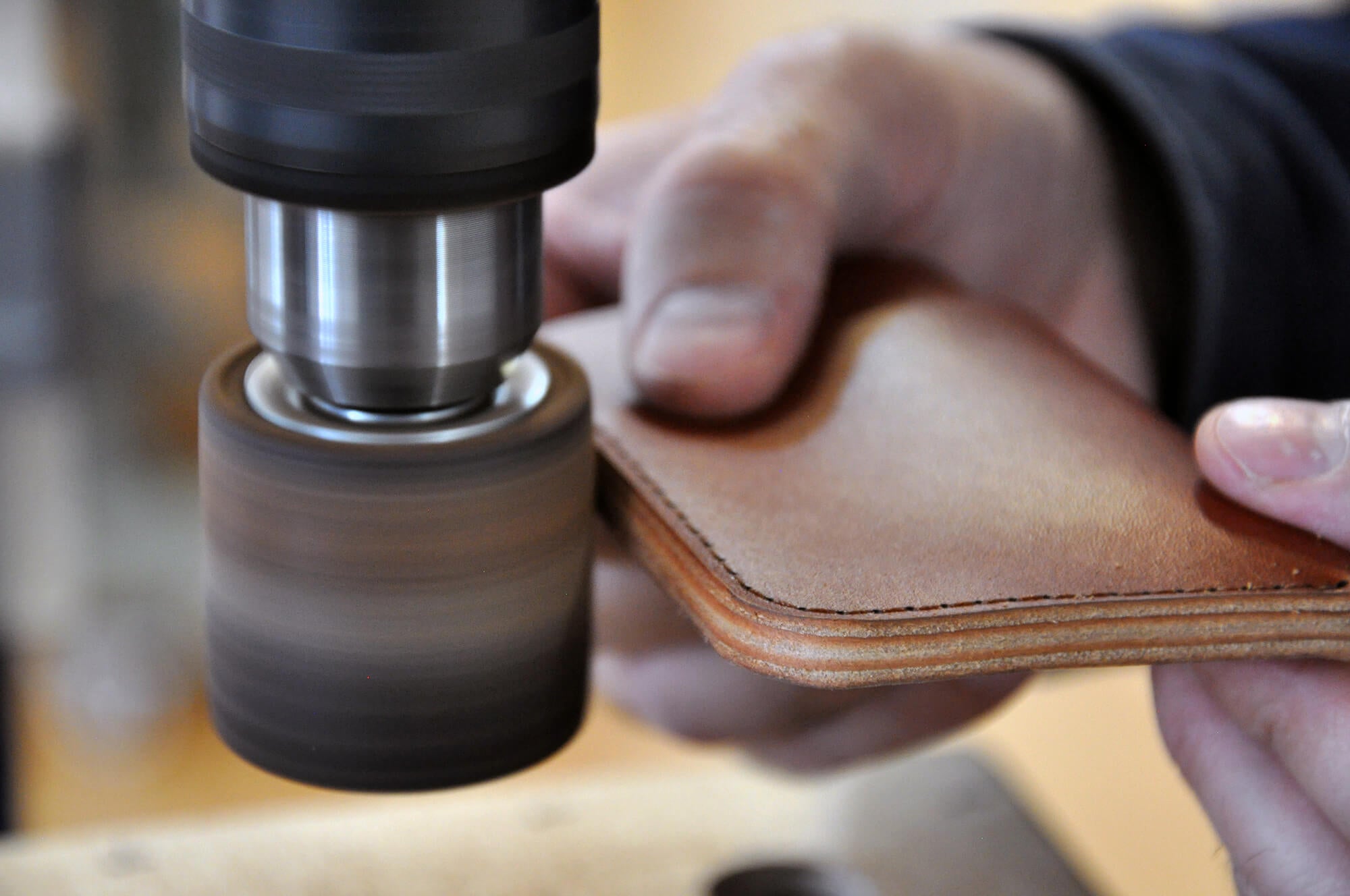 Hands finishing the edges of a Half Wallet.