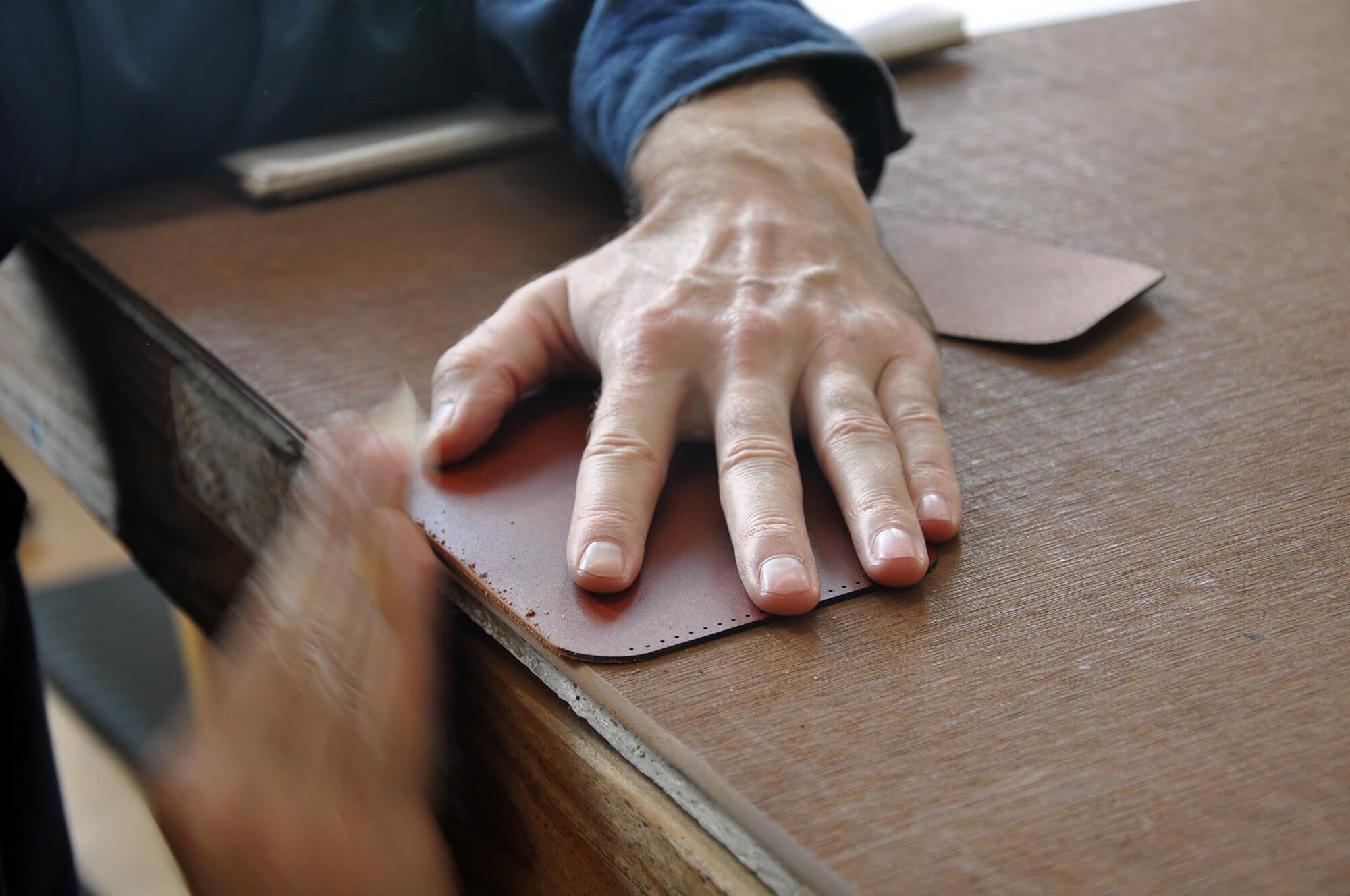 Hands sanding pieces of a Half Wallet.